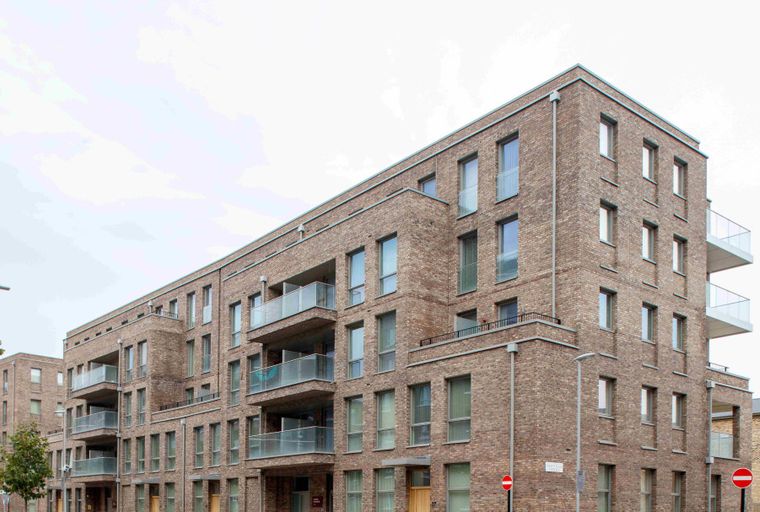 A modern brick apartment building with glass balconies and numerous windows.