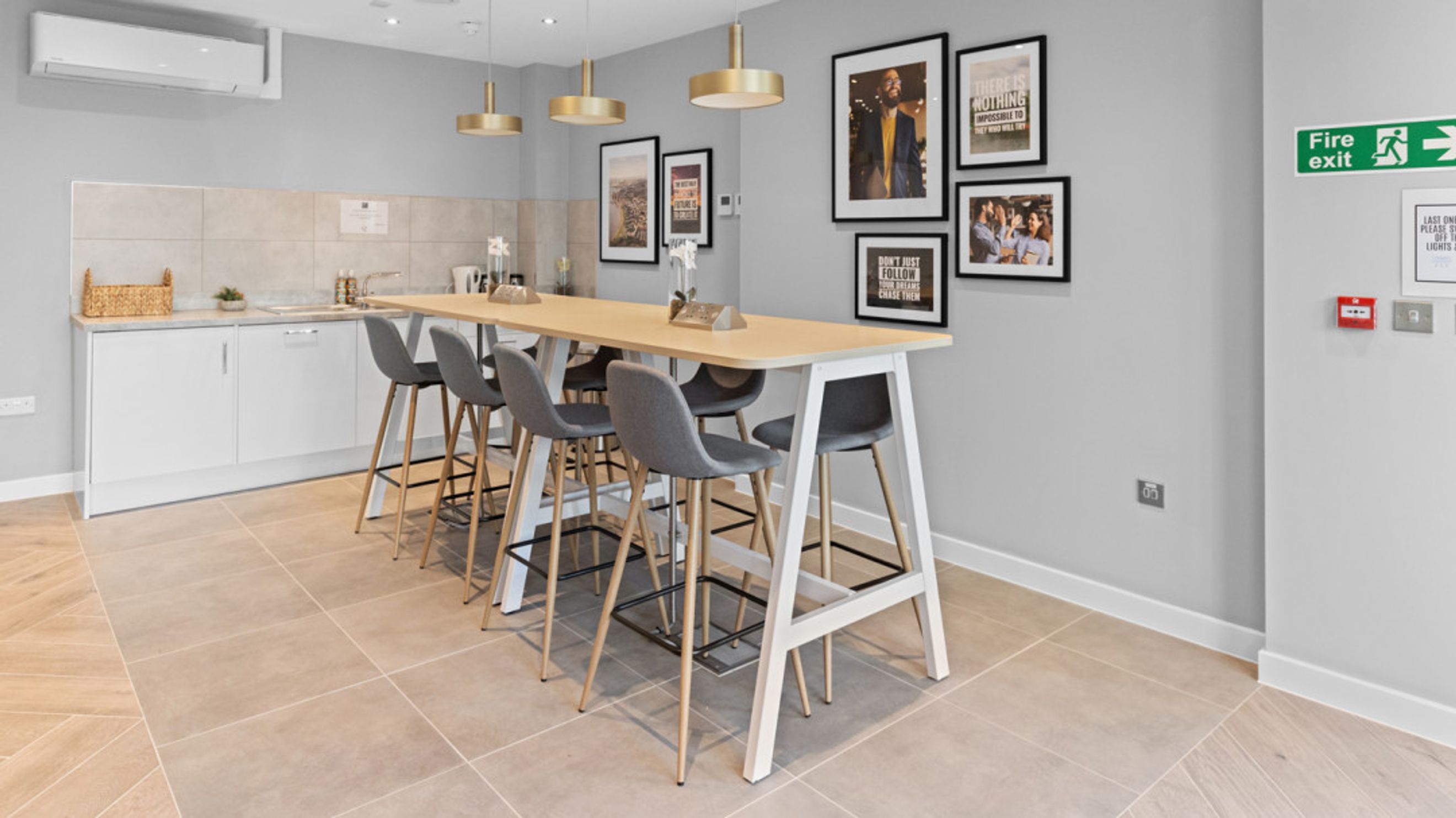 A communal kitchen with a long breakfast bar, stools, and artwork on the wall.