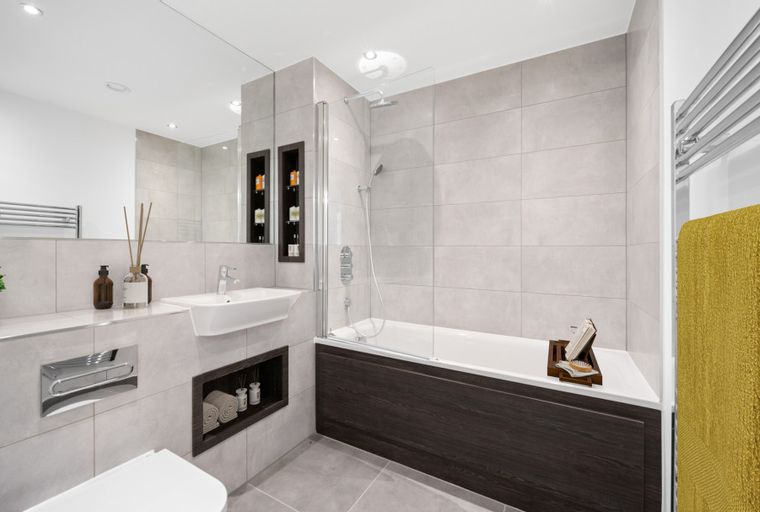 A bathroom with a bathtub, sink, and tiled walls.