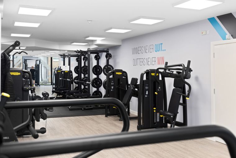 A gym with weight machines and motivational quotes on the wall.
