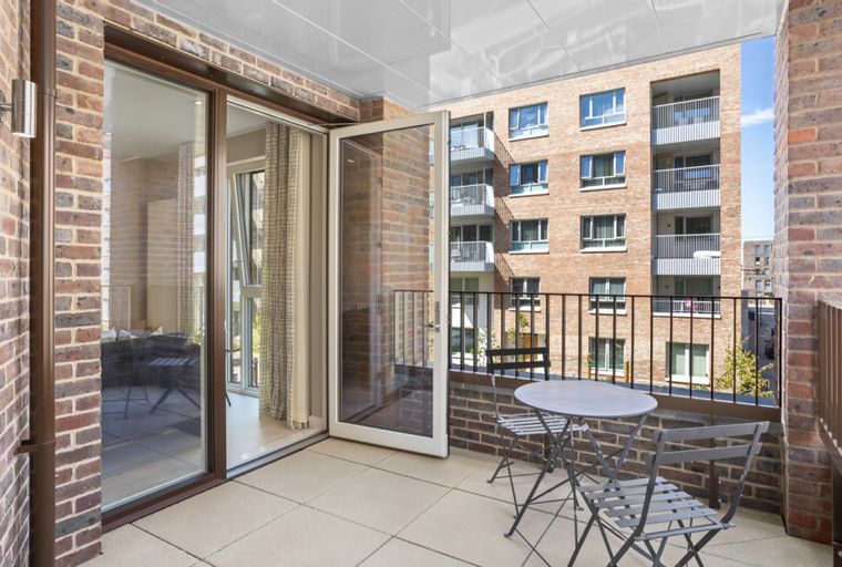 A balcony with a table and chairs overlooking a brick building.