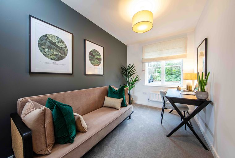 A room with a sofa, desk, and two framed pictures on the wall.