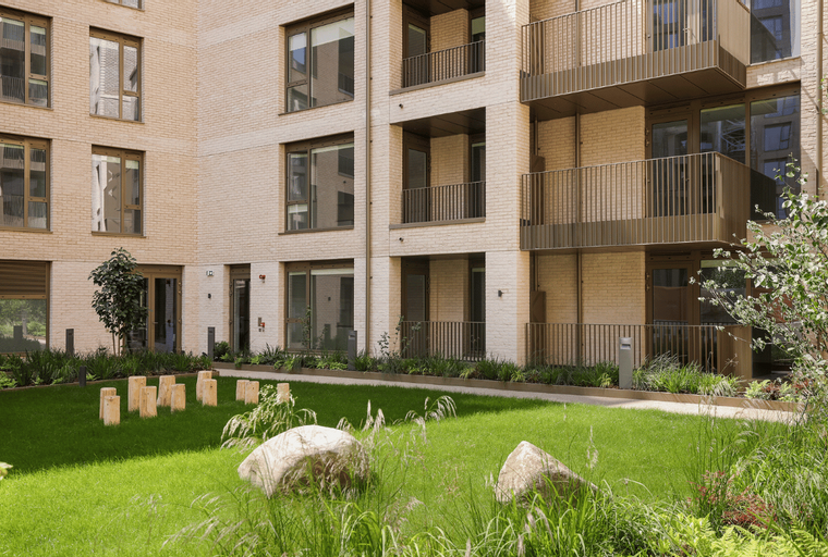 A courtyard with a lawn, rocks, and a modern apartment building.