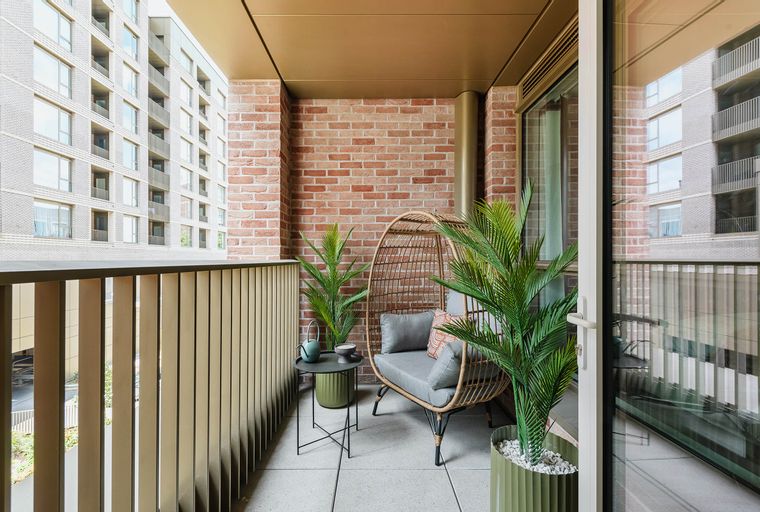 A balcony with an egg chair, plants, and a small table.