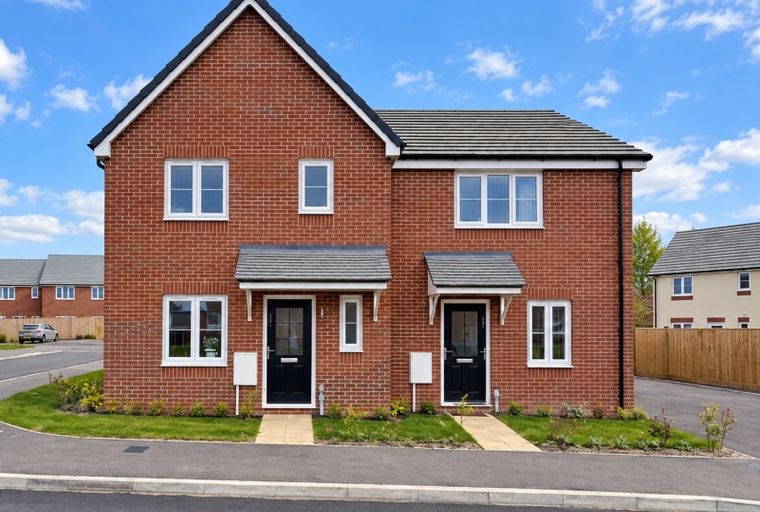 A pair of semi-detached brick houses with black front doors and white-framed windows under a blue sky.