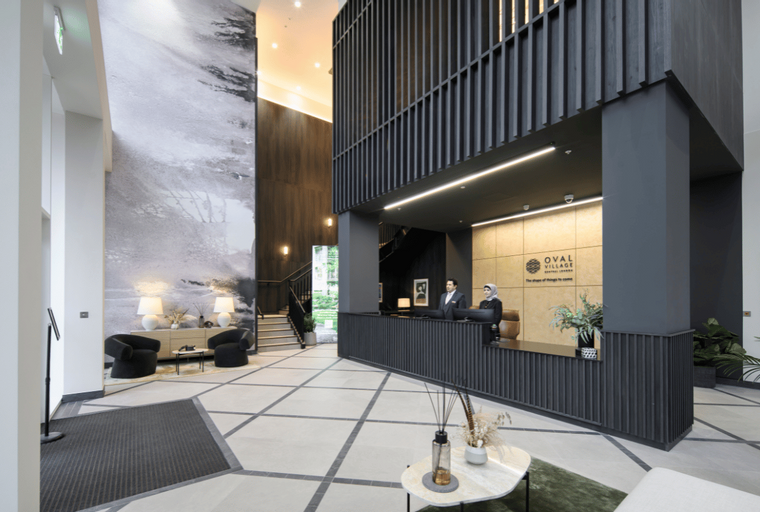 A modern lobby with a reception desk, two receptionists, and contemporary seating.
