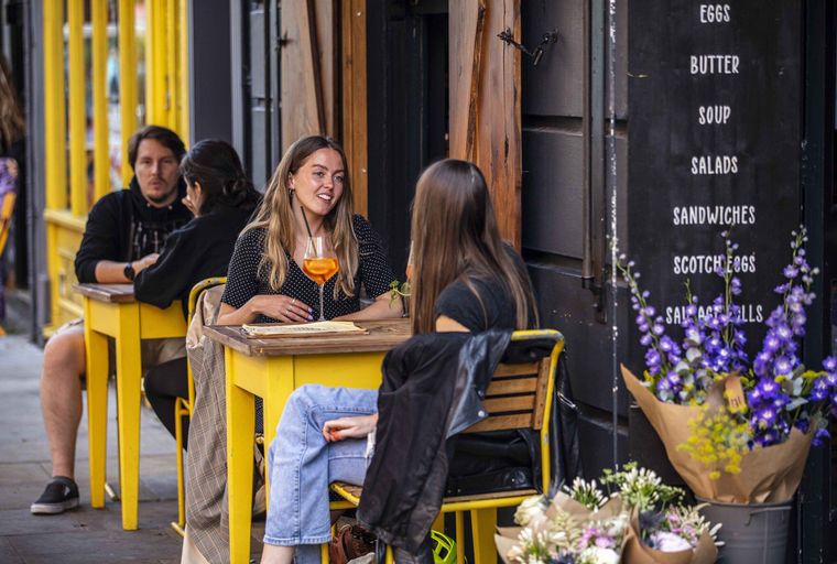A group of people sitting at yellow tables outside a cafe.