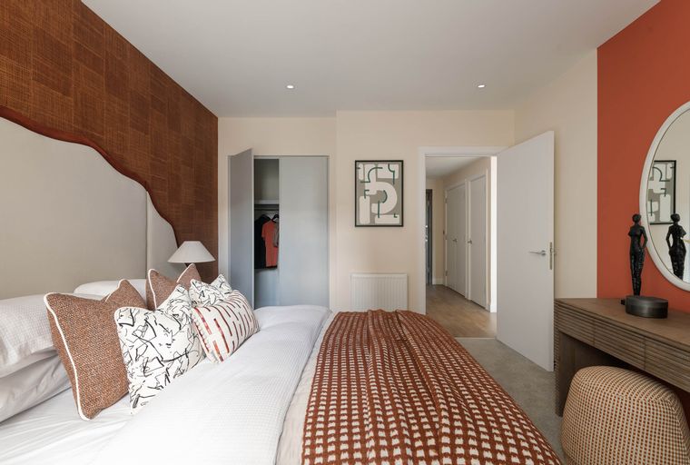 A bedroom with a bed, pillows, a blanket, a closet, and a vanity.