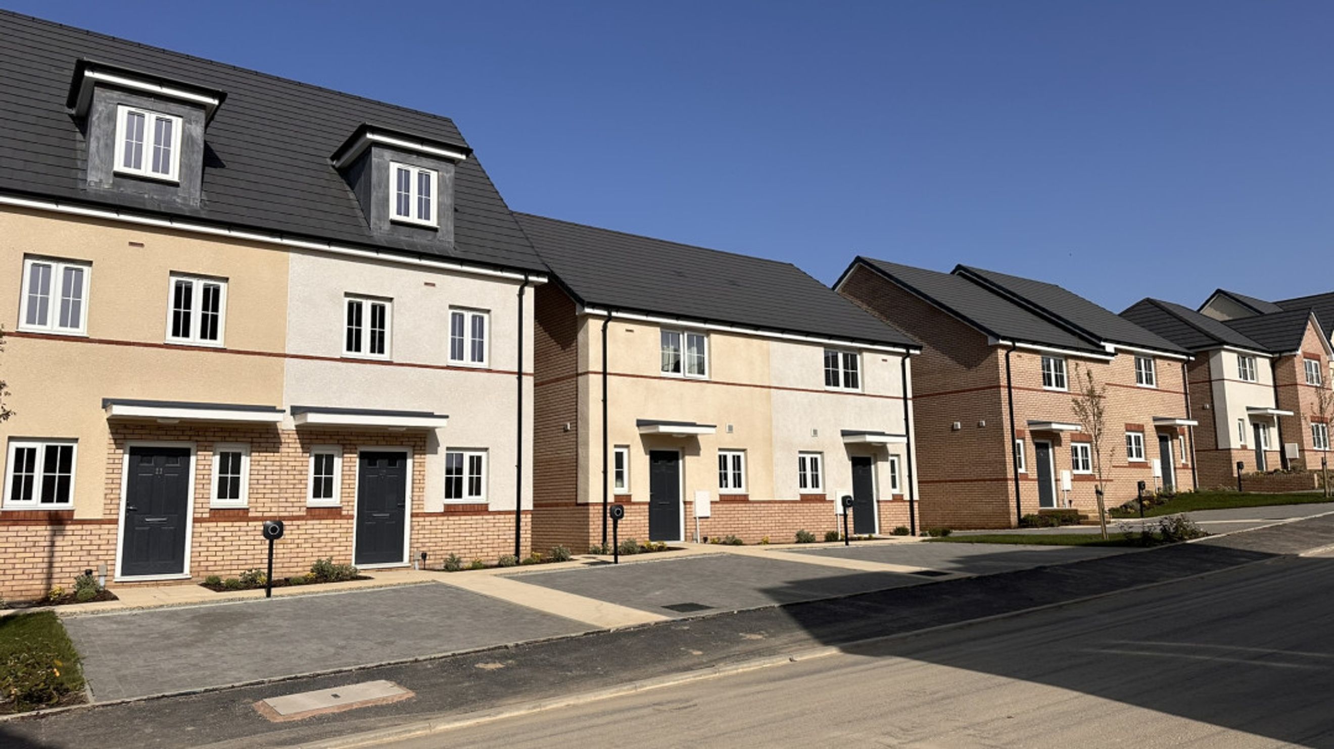 A row of modern townhouses with stucco and brick exteriors under a clear blue sky.