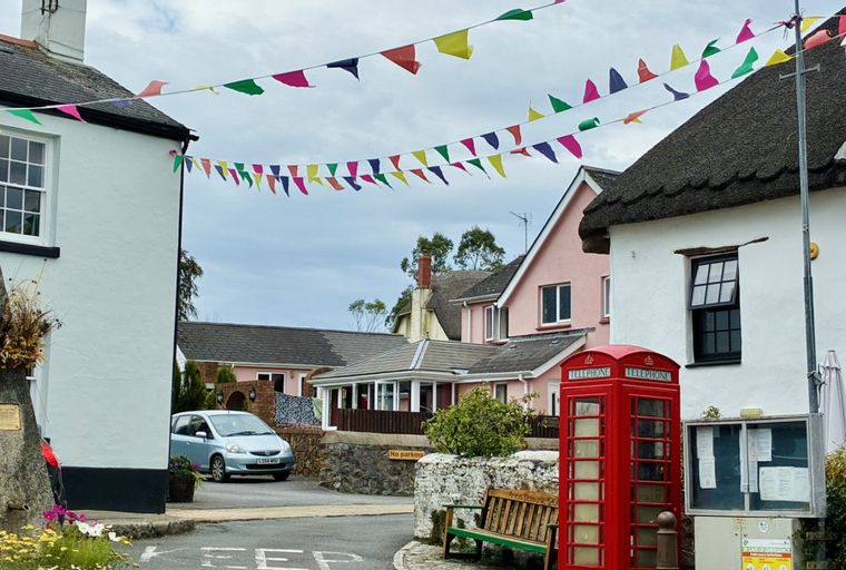A red telephone box and a pub with bunting strung across a village street.