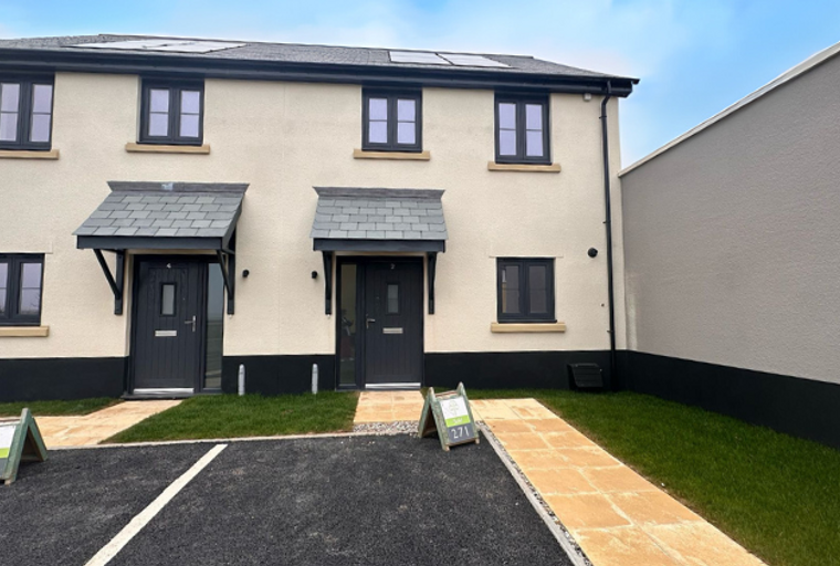 A pair of semi-detached houses with dark grey windows and doors, each with a small porch over the entrance.