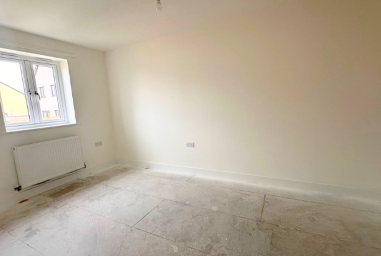 A room with a window, a radiator, and a tiled floor.
