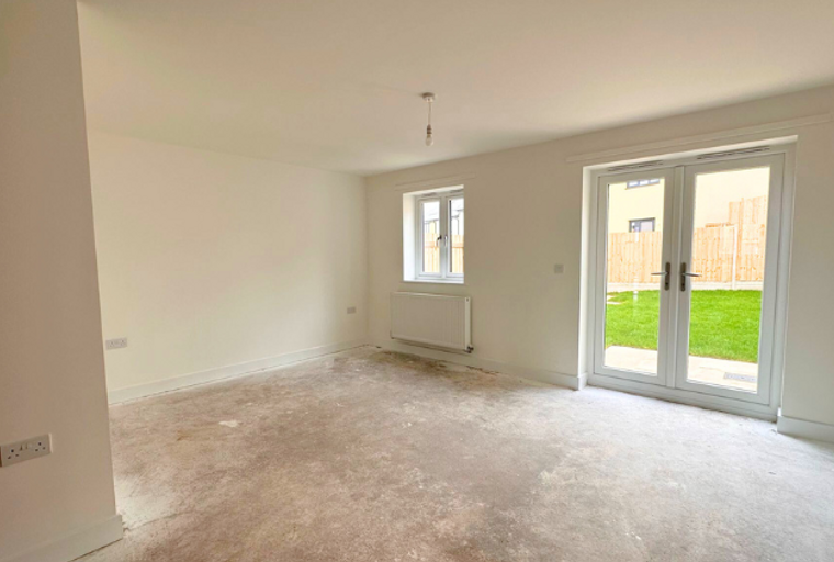 A living room with a window, radiator, and double doors leading to a garden.