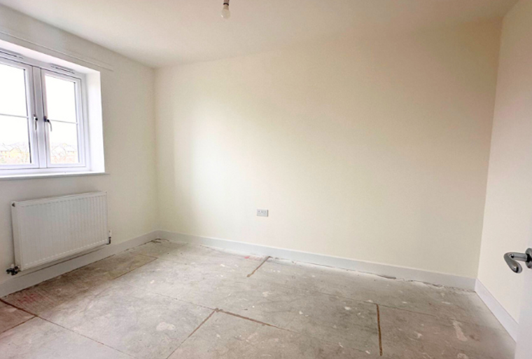 A room with a window, radiator, and electrical socket.