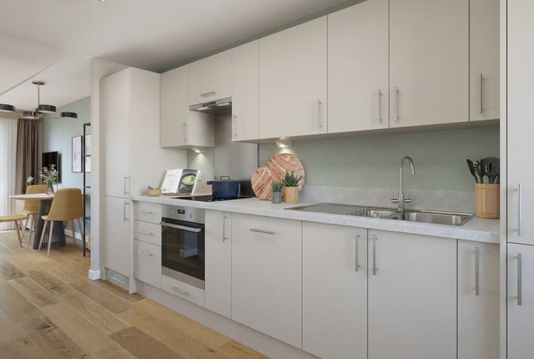 A modern kitchen with light-colored cabinets, a built-in oven, and a double sink.