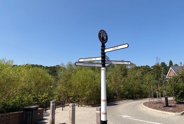 A signpost with directions to the brewery, entrance, and Parliament Square, with the Badger Brewery logo at the top.