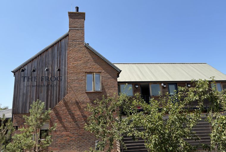 A building with a brick chimney, wooden siding, and a metal roof.