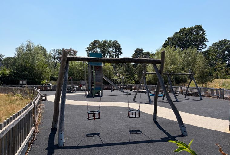 A playground with swings, a play structure, and a slide.
