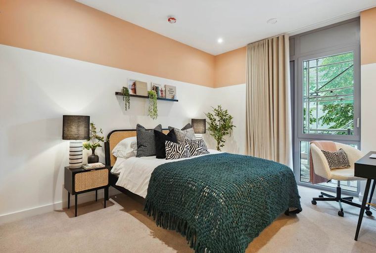 A bedroom with a bed, bedside table, and a window.