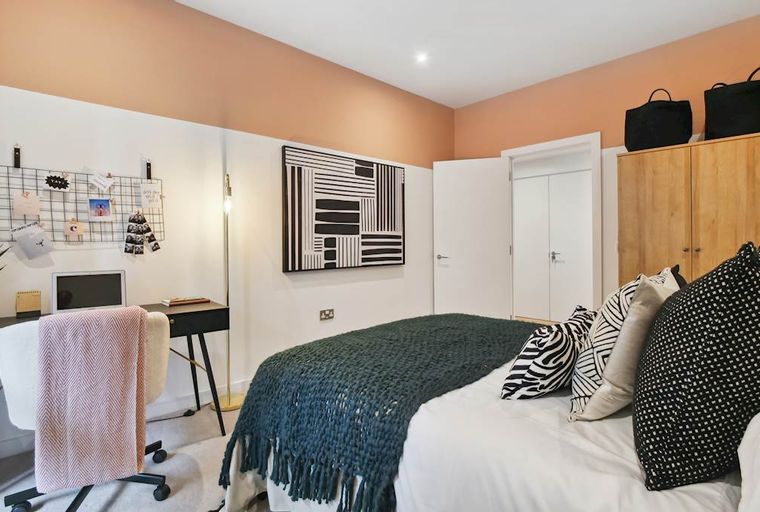 A bedroom with a bed, desk, chair, and wardrobe.