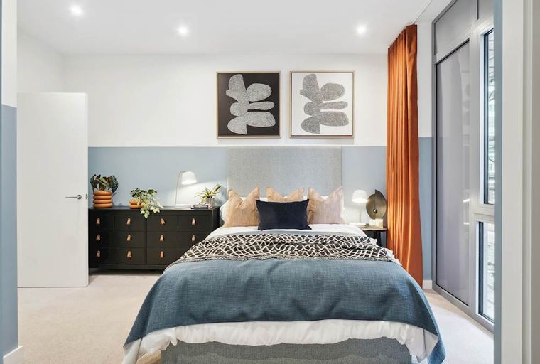A bedroom with a bed, dresser, and artwork.