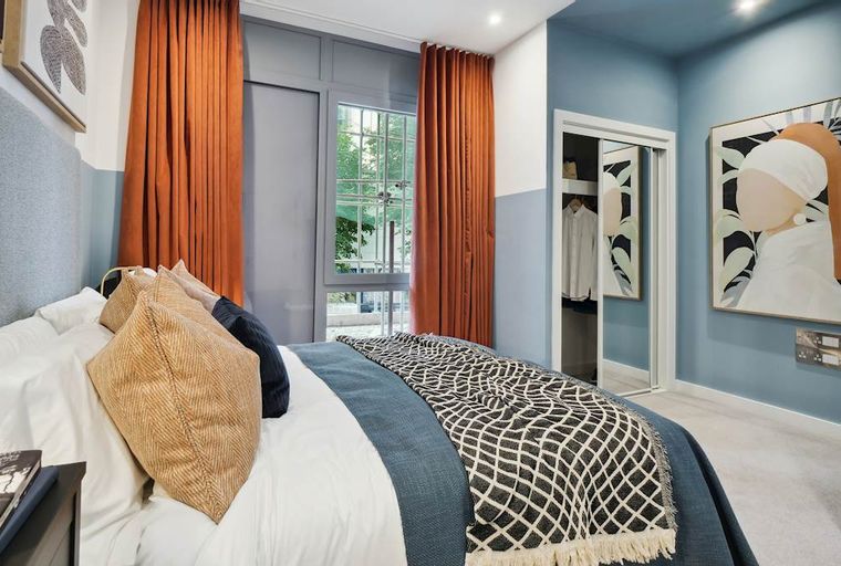 A bedroom with a bed, pillows, curtains, and artwork.