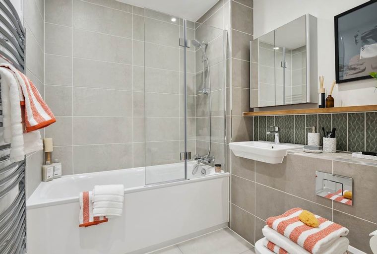 A bathroom with a bathtub, sink, and mirrored cabinet.