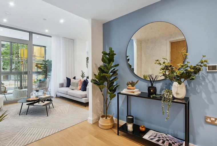 A living room with a sofa, coffee table, and a large round mirror on a blue wall.