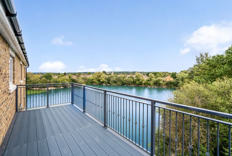 A balcony with a view of a lake and trees.