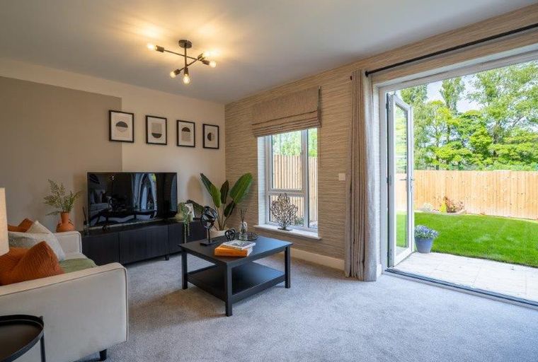 A living room with a television, coffee table, and open glass doors leading to a backyard.