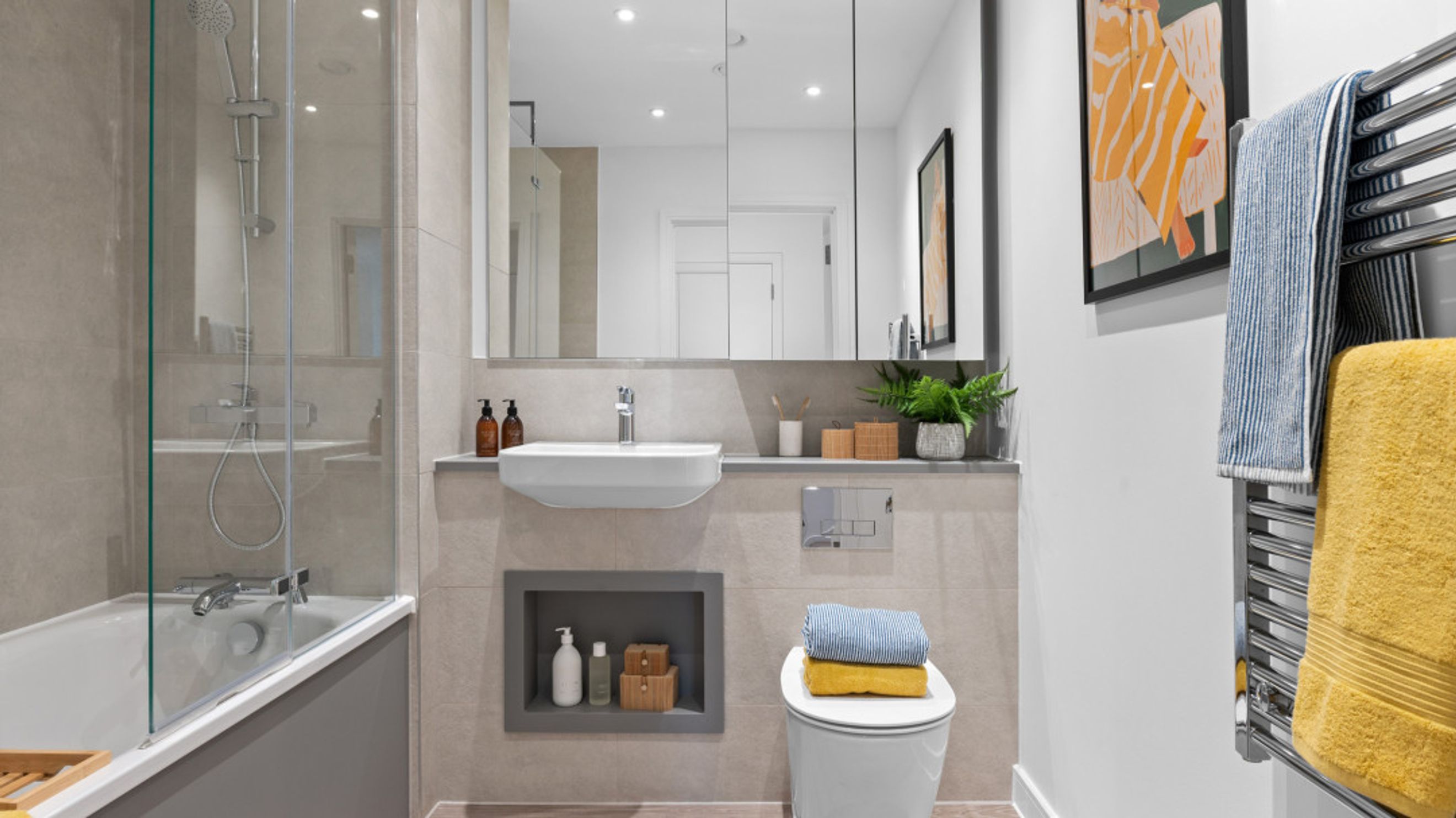 A modern bathroom with a bathtub, sink, toilet, and mirrored cabinet.