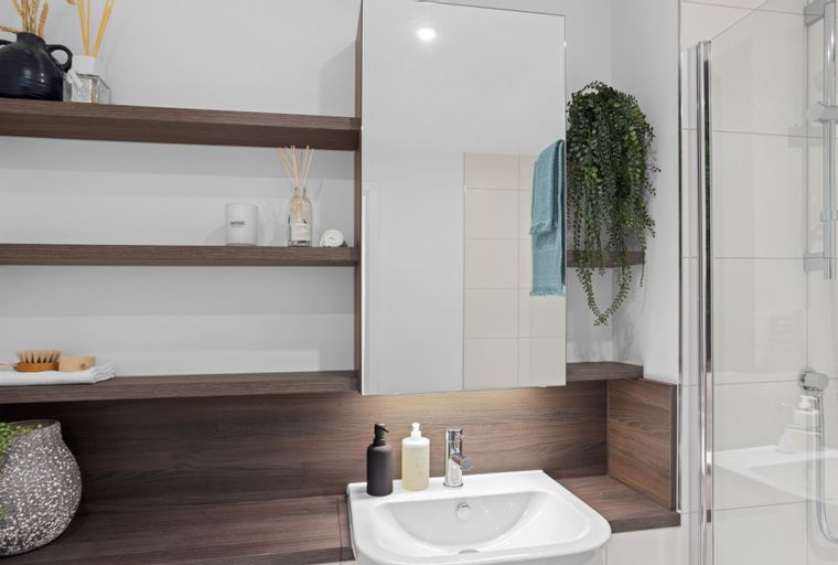 A bathroom with a sink, mirror, shelves, and a shower.