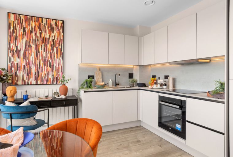 A modern kitchen and dining area with a desk and artwork.