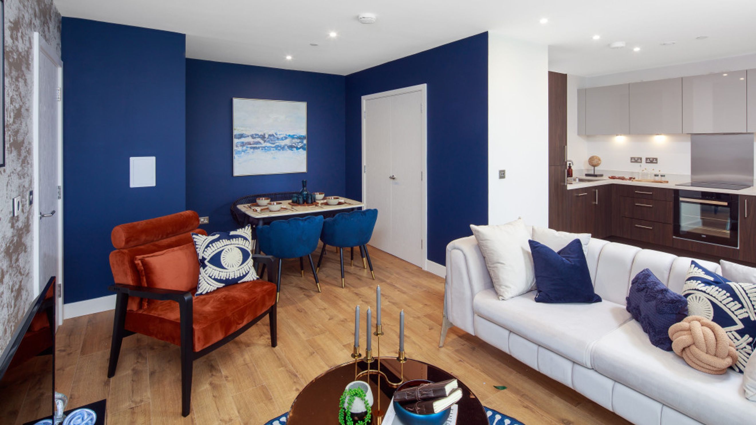 A living room and kitchen area with a sofa, chairs, and dining table.