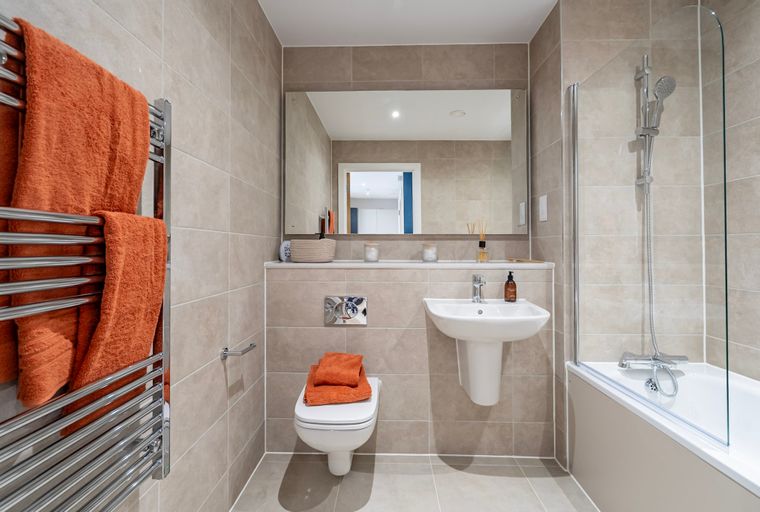 A bathroom with a toilet, sink, bathtub, and mirror.