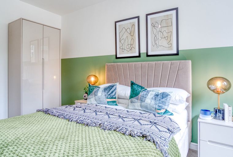 A bedroom with a bed, bedside tables, lamps, and a wardrobe.