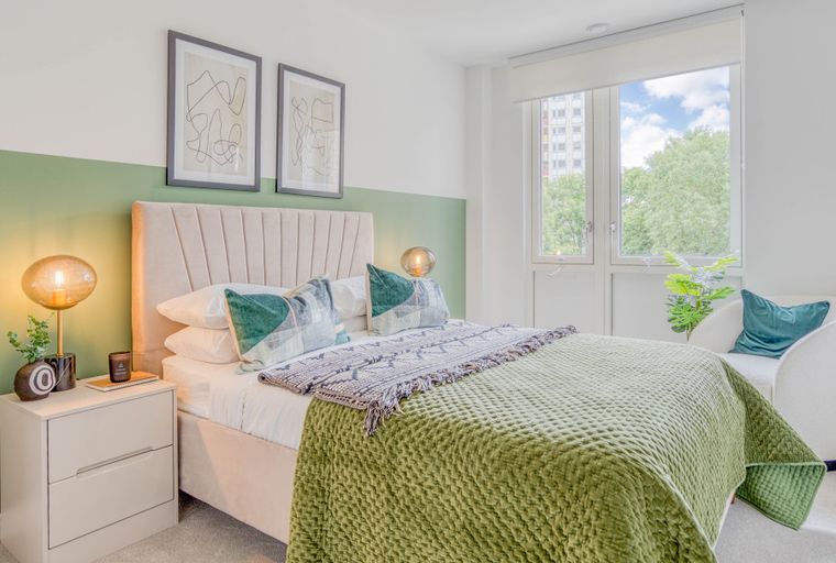 A bedroom with a bed, bedside table, and a window.