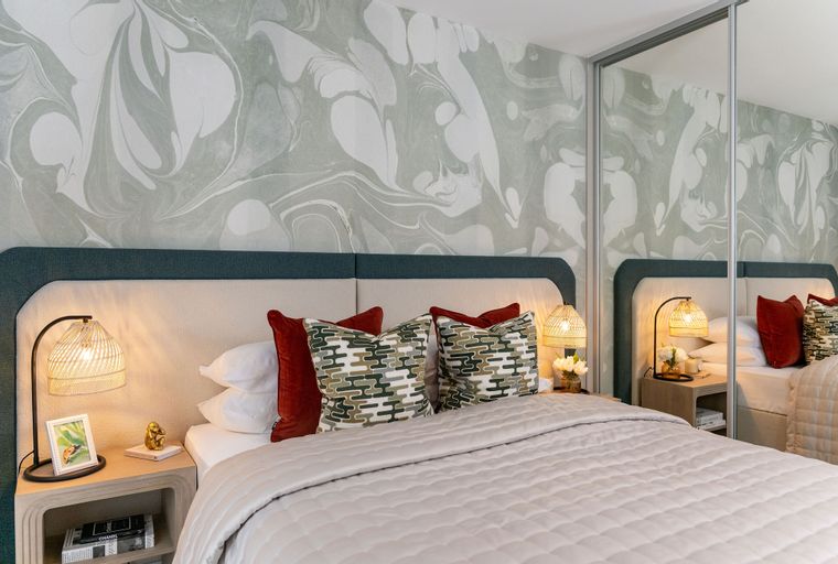 A bedroom with a bed, pillows, bedside tables, and lamps.