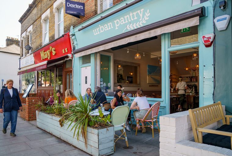 A street view of two storefronts, one a cafe called 'urban pantry' and the other a restaurant called 'May's'.