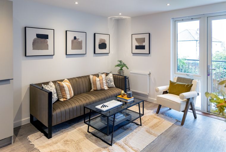 A living room with a sofa, coffee table, armchair, and artwork on the wall.