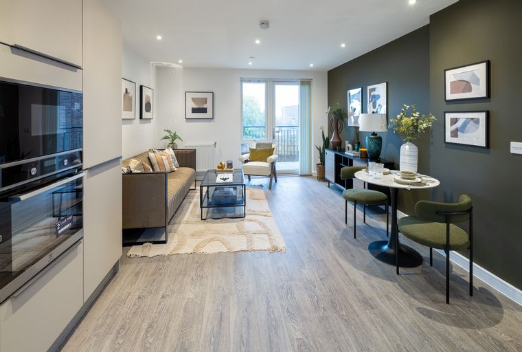 A living room and kitchen area with a sofa, coffee table, dining table, and kitchen appliances.
