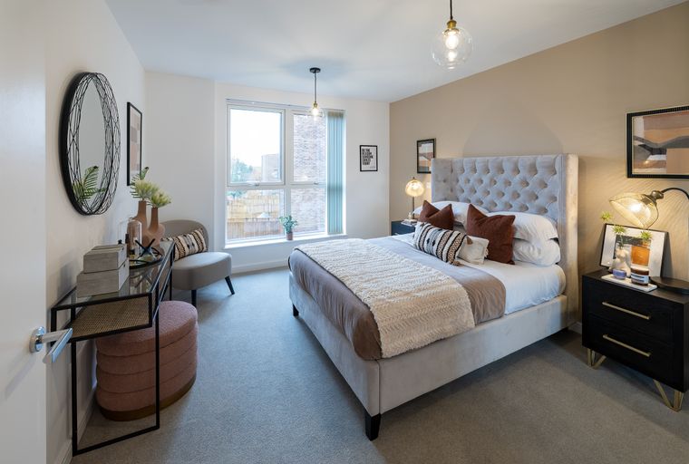 A bedroom with a bed, nightstand, and a vanity table.