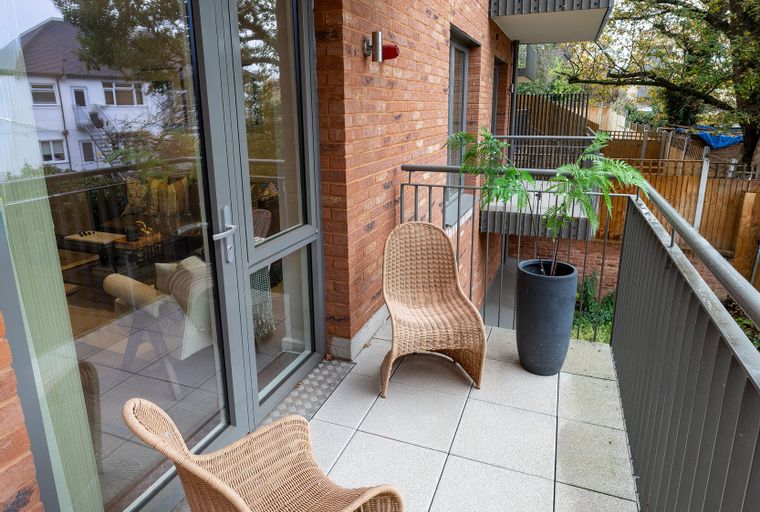 A balcony with two wicker chairs and a potted plant.