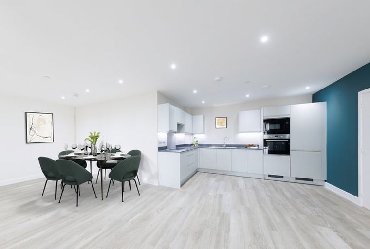 A dining area and kitchen with white cabinets, a dark round table with chairs, and a painting on the wall.