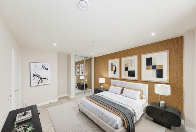 A bedroom with a bed, nightstands, and artwork.