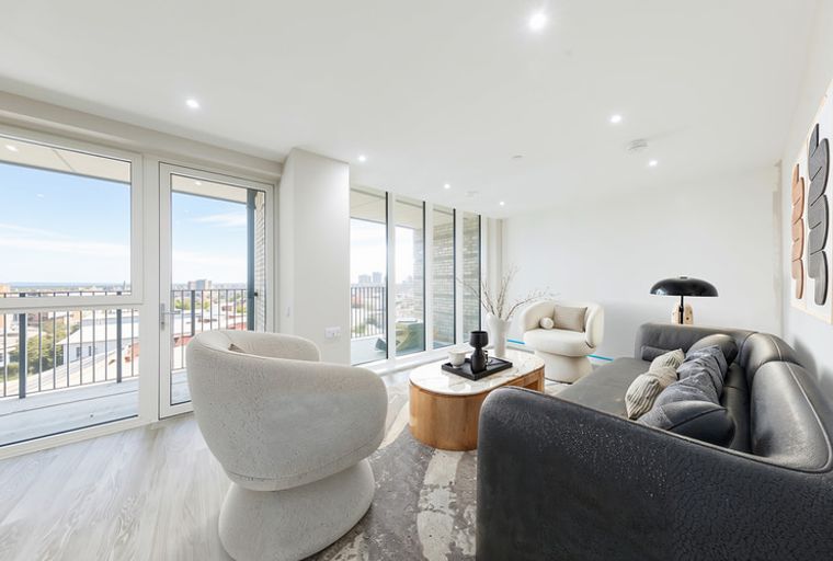 A living room with a sofa, chairs, and a coffee table in front of large windows.