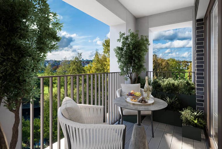A balcony with two chairs, a table, and a view of trees and buildings.