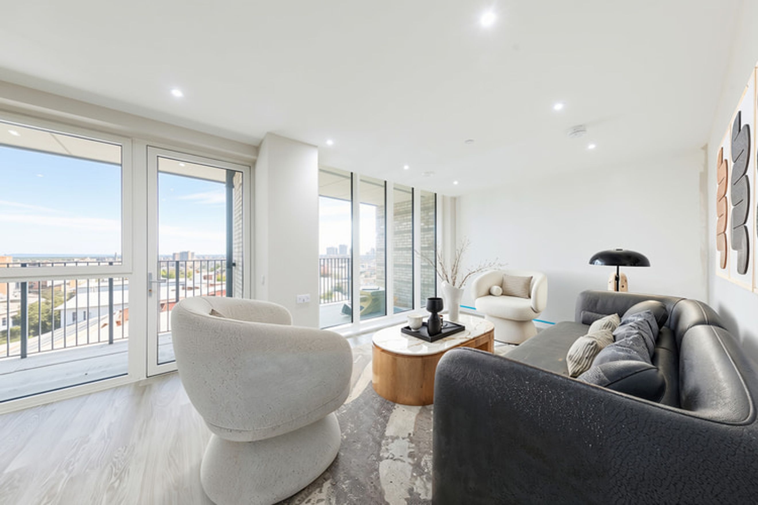 A living room with a sofa, chairs, and a coffee table in front of large windows.
