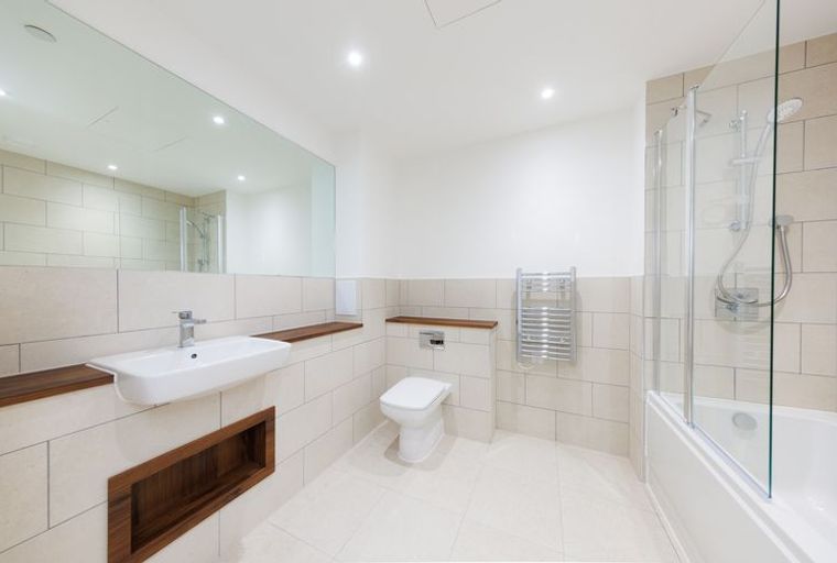 A bathroom with a sink, toilet, bathtub with a shower, and a heated towel rail.
