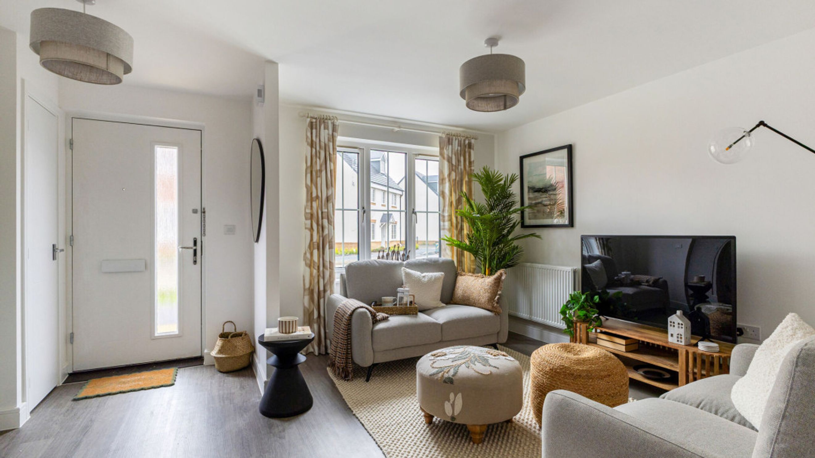 A living room with a loveseat, ottoman, and a television.